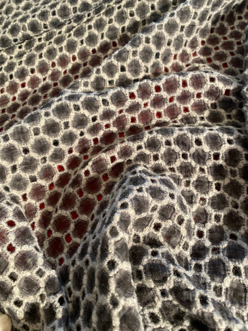 Peut inclure: Gros plan sur un tissu noir et blanc avec un motif g&eacute;om&eacute;trique. Le tissu a une texture en relief et une subtile teinte rouge.