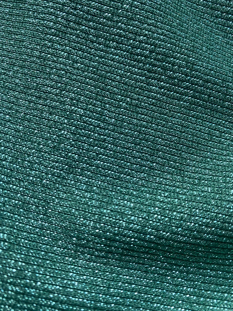 May include: Close-up of a teal fabric with a textured, ribbed pattern. The fabric has a subtle shimmer.