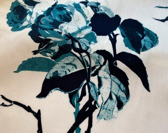 May include: A white fabric with a teal and black floral print. The print features a large rose with leaves and stems.