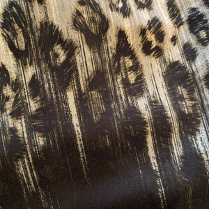 May include: Abstract fabric with a black and white leopard print pattern. The fabric has a textured, brushed look.