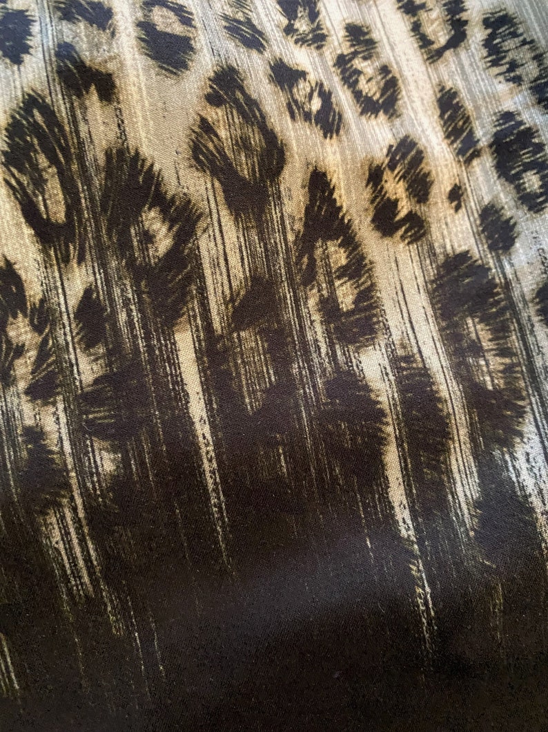 May include: Abstract fabric with a black and white leopard print pattern. The fabric has a textured, brushed look.