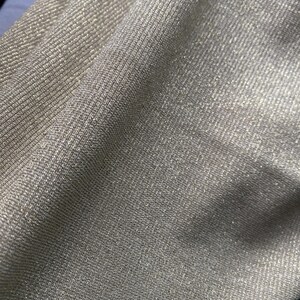 May include: Close-up of a shimmery gold fabric with a ribbed texture. The fabric has a subtle sparkle and a soft, drapey feel.