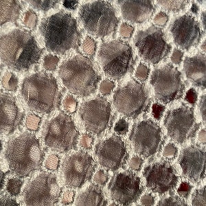 Peut inclure: Gros plan sur un tissu gris et blanc avec un motif r&eacute;p&eacute;titif de petits trous ronds. Le tissu a un aspect textur&eacute; et tiss&eacute;.