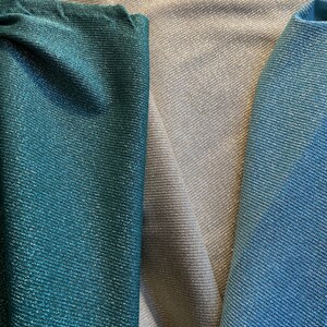 May include: Close-up of three fabric swatches in teal, silver, and light blue. The fabrics have a subtle shimmer and a textured weave.