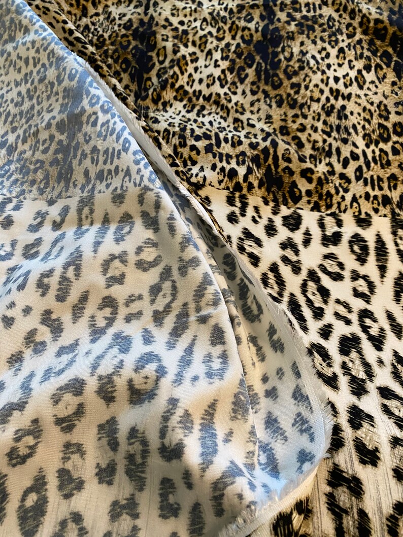 May include: Close-up of a fabric with a leopard print pattern. The fabric is a mix of brown, black, and white.