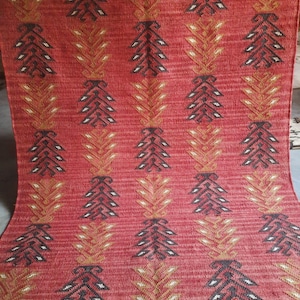 Puede incluir: Alfombra roja, negra y dorada con estampado y borde de flecos. La alfombra tiene un diseño geométrico con motivos repetidos.