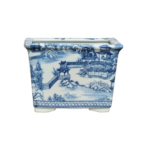 May include: A rectangular blue and white porcelain planter with a traditional Chinese landscape design. The planter has a raised rim and four small feet.