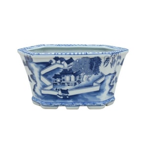 May include: A blue and white porcelain planter with a hexagonal shape and a design of a Chinese village scene.