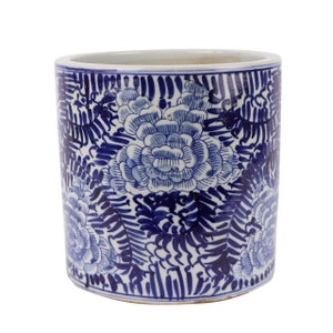 May include: A white ceramic planter with a blue and white floral design. The planter is cylindrical in shape and has a wide mouth.