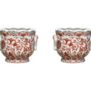 May include: Two white ceramic planters with red floral designs and decorative handles in the shape of stylized faces.