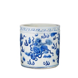 May include: A white ceramic planter with a blue and white design. The planter features a repeating pattern of stylized clouds and a mythical creature. The planter has a blue and white border around the top.