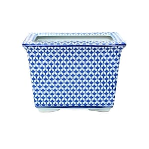 May include: A white ceramic planter with a blue and white geometric pattern. The planter has a rectangular shape with rounded corners and a slightly raised rim.