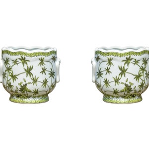 May include: Two white ceramic planters with a scalloped rim and handles. The planters are decorated with a green palm tree design. The rim and base have a green border. These planters are ideal for indoor or outdoor use.