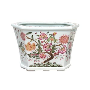 May include: White octagonal ceramic planter with a floral design. The planter features pink, red, and yellow flowers with green leaves.