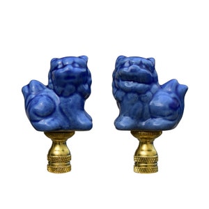 May include: A pair of blue ceramic Foo Dog lamp finials with gold bases. The Foo Dogs are facing opposite directions.