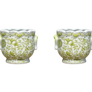 May include: Two white ceramic planters with green floral designs and decorative handles. The planters have a scalloped rim.