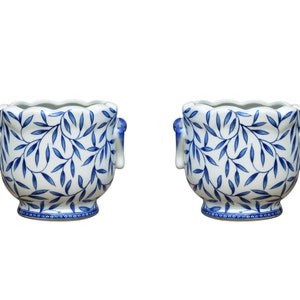 May include: Two white ceramic planters with blue floral designs and elephant-shaped handles.