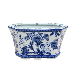 May include: A white ceramic planter with a blue floral design. The planter has an octagonal shape and a wide, shallow base.