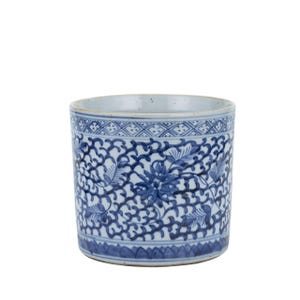 May include: A white ceramic cup with a blue and white floral pattern. The cup is cylindrical in shape and has a slightly flared rim.