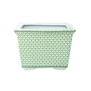 May include: A white ceramic planter with a green and white geometric pattern. The planter has a rectangular shape and a wide, flat base.