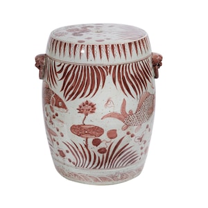 May include: A white ceramic garden stool with red painted fish and lotus flower designs. The stool has two lion head handles on the sides.
