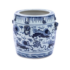 May include: A white ceramic planter with blue and white floral and dragon designs. The planter has four lion head handles.