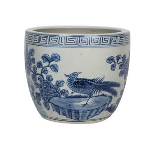 May include: A white ceramic planter with a blue and white floral design and a bird. The planter has a geometric pattern around the top rim.