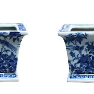 May include: Two blue and white ceramic planters with a floral and bird design. The planters have a square base and a rectangular body.