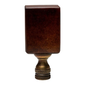 May include: A dark brown wooden lamp finial with a gold metal base. The finial is square shaped and has a smooth finish.
