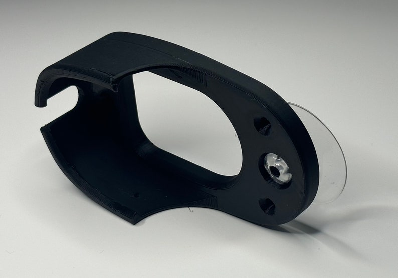 Puede incluir: Soporte para tel&eacute;fono de pl&aacute;stico negro con una ventosa en la parte posterior. El soporte tiene un dise&ntilde;o curvo para adaptarse a un tel&eacute;fono.