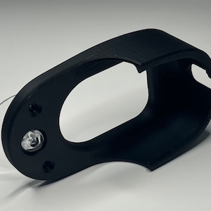 Puede incluir: Soporte para tel&eacute;fono de pl&aacute;stico negro con una ventosa en la parte posterior. El soporte tiene un dise&ntilde;o curvo y una gran abertura para un tel&eacute;fono.