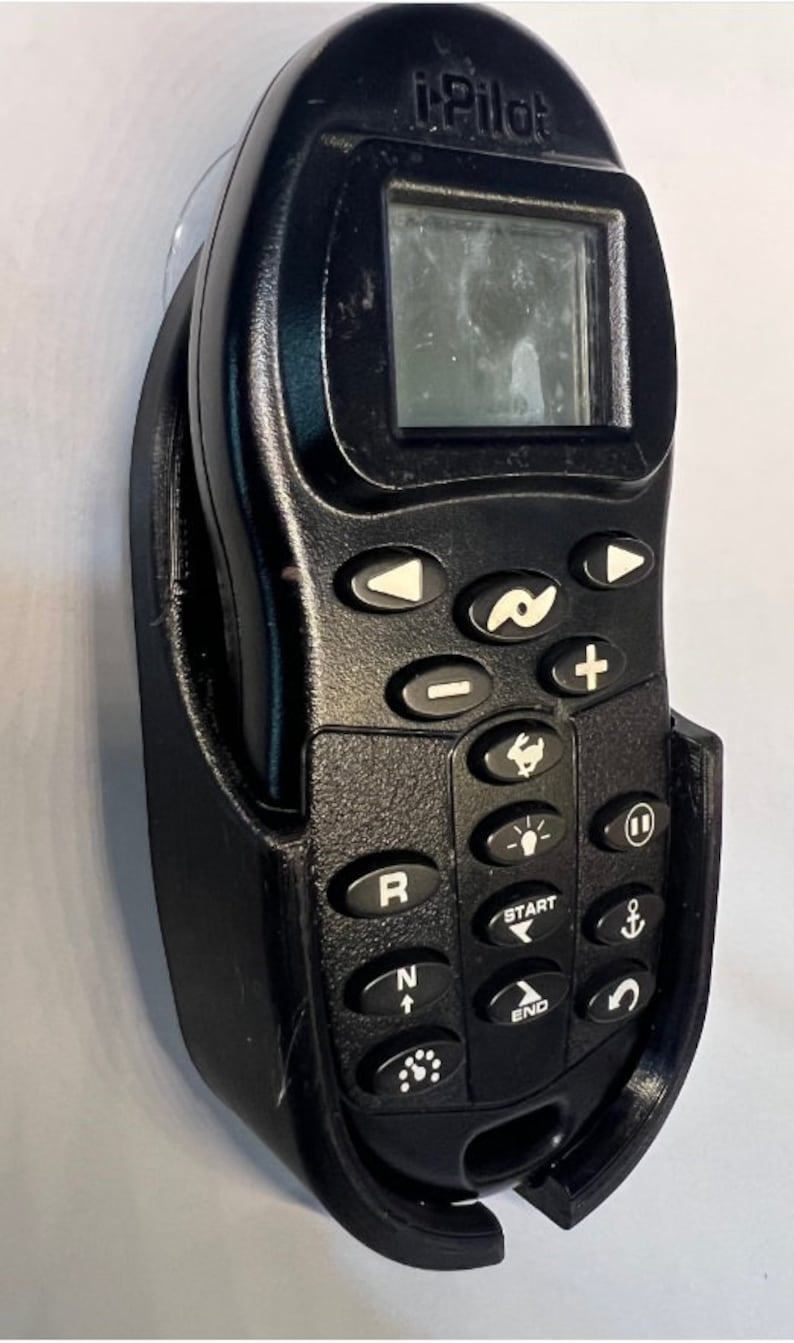 Puede incluir: Un mando a distancia i-Pilot negro con una pantalla y una variedad de botones. El mando a distancia est&aacute; montado en un soporte de pl&aacute;stico negro.