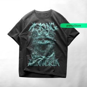 May include: A black t-shirt with a teal blue graphic print of a skull wearing a samurai helmet. The text "Asking Alexandria" is printed below the skull.