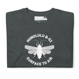 May include: Dark grey t-shirt with a white circle graphic featuring a stylized insect with the text "HONOLULU B-52 SURFACE TO AIR".