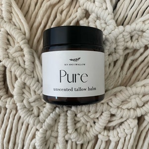 May include: A brown glass jar with a black lid containing an unscented tallow balm. The jar has a white label with the text "Sky and Swallow Pure unscented tallow balm".