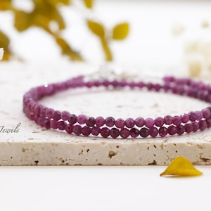 May include: A delicate double-strand bracelet made with small, faceted, pink gemstone beads. The bracelet is made with a silver clasp.