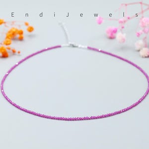 May include: A delicate pink gemstone necklace with a silver clasp. The necklace is made of small, faceted gemstones that are strung together to create a simple and elegant design.
