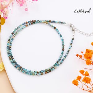 Op de afbeelding: Een delicate ketting met twee rijen turquoise en bruine edelsteen kralen. De ketting heeft een zilveren sluiting en een verlengketting.