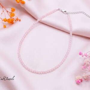 May include: A delicate necklace featuring small, round, pale pink beads strung together. The necklace includes a silver-toned metal lobster clasp and an adjustable extender chain. The text EndiJewels is visible in the bottom left corner.