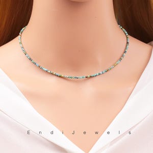 Op de afbeelding: Een delicate turquoise en groene kralenketting op een witte achtergrond. De ketting is gemaakt van kleine, onregelmatige kralen en is ongeveer 40 cm lang.