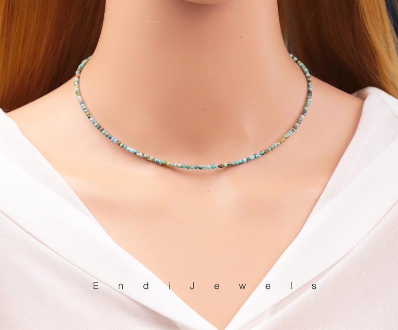 Op de afbeelding: Een delicate turquoise en groene kralenketting op een witte achtergrond. De ketting is gemaakt van kleine, onregelmatige kralen en is ongeveer 40 cm lang.