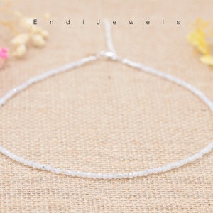 Może przedstawiać: Delikatny naszyjnik z białych koralików ze srebrnym zapięciem. Naszyjnik wykonany jest z małych, okrągłych koralików i idealnie nadaje się do warstwowego noszenia.