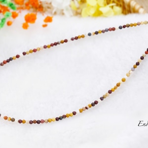 May include: A multi-colored stone bead necklace with a silver clasp. The beads are small and round, and they are arranged in a random pattern. The necklace is about 18 inches long.
