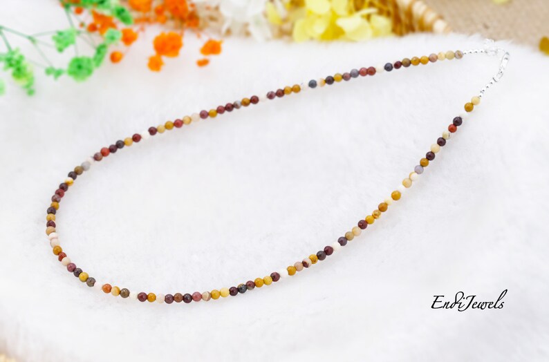 May include: A multi-colored stone bead necklace with a silver clasp. The beads are small and round, and they are arranged in a random pattern. The necklace is about 18 inches long.