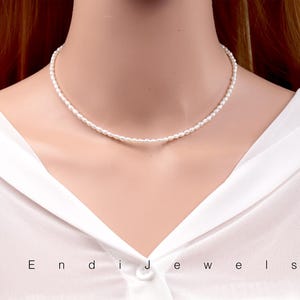 May include: A simple white pearl choker necklace. The necklace is made of small, round pearls that are strung together on a thin silver chain.