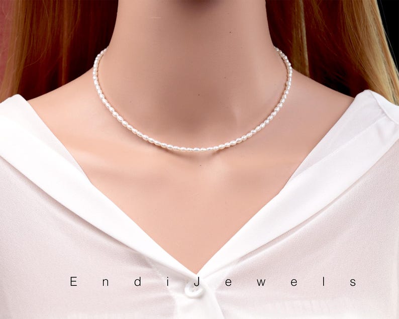 May include: A simple white pearl choker necklace. The necklace is made of small, round pearls that are strung together on a thin silver chain.