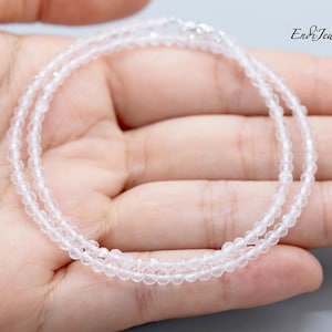 Op de afbeelding: Een delicate, heldere kwarts kralenketting met een zilveren sluiting. De ketting bestaat uit kleine, ronde kralen, waardoor een subtiele, elegante uitstraling ontstaat. De afbeelding bevat de tekst "End & Jewels".