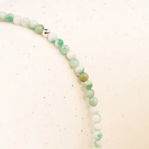 May include: A green and white beaded bracelet with a silver bead accent.
