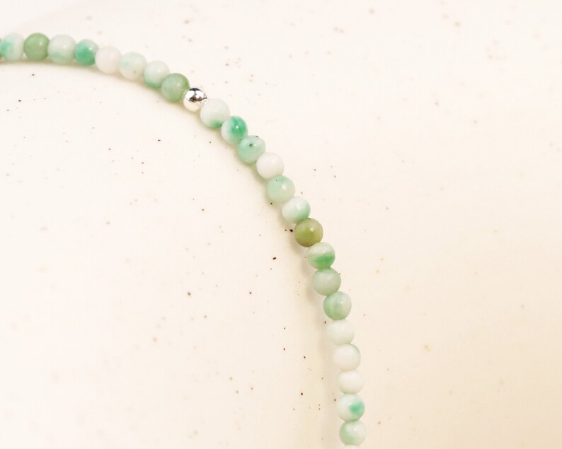 May include: A green and white beaded bracelet with a silver bead accent.