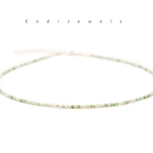 May include: A delicate green gemstone necklace with a silver clasp. The necklace is made of small, round beads and is perfect for layering.